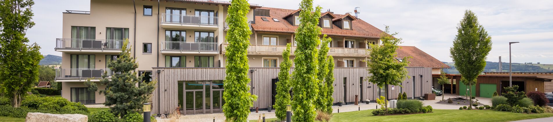 Hotelansicht von vorne mit Weg und Baumbepflanzung