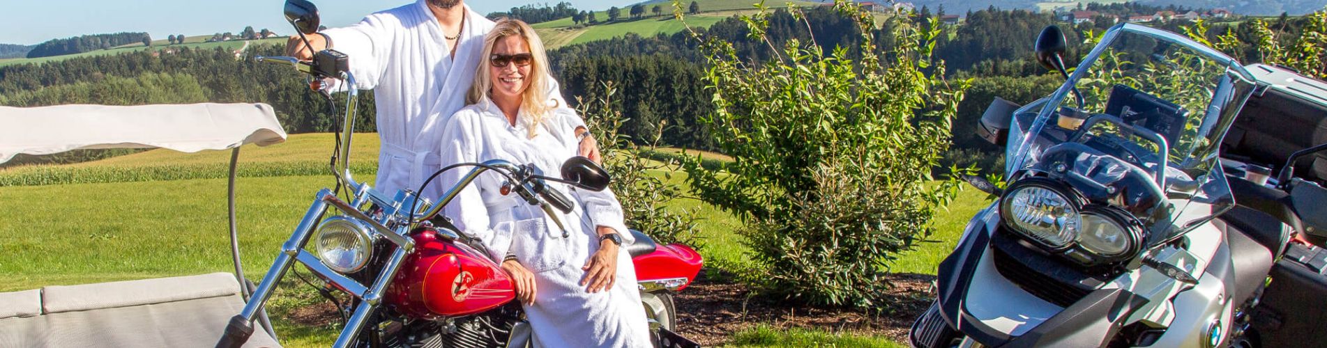 Pärchen im Bademantel auf Motorrad im Wellnessgarten