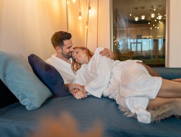 Paar im Bademantel kuschelt auf Schaukelliege