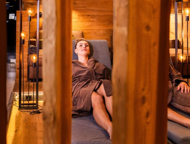 Dame im Bademantel liegt entspannt auf einer bequemen Liege