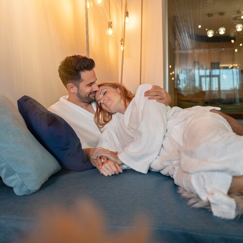 Paar im Bademantel kuschelt auf Schaukelliege