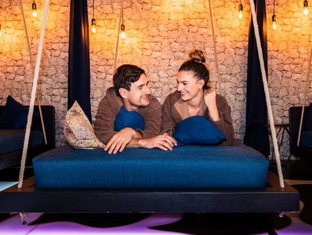 Paar liegt auf einer großen Schaukelliege im Ruheraum