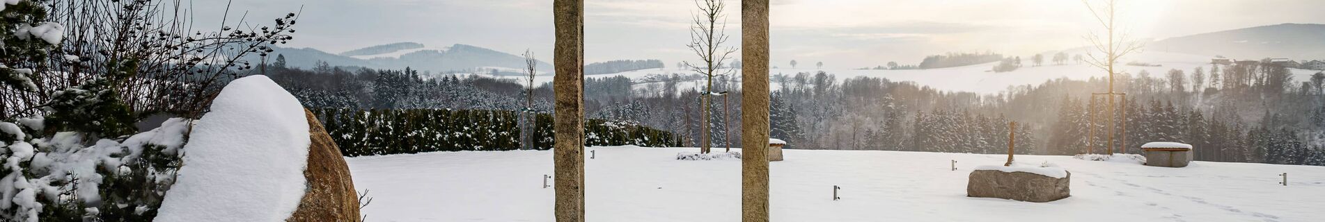 Winterlicher Wellnessgarten mit steinernem Torbogen und Sonnenuntergang