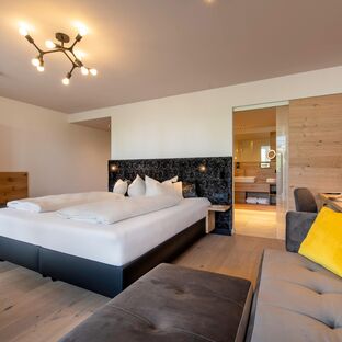 Modernes Zimmer mit Boxspringbett, Sofa, Durchgang zu großem Badezimmer