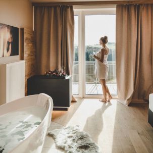 Frau mit Handtuch blickt aus dem Fenster
