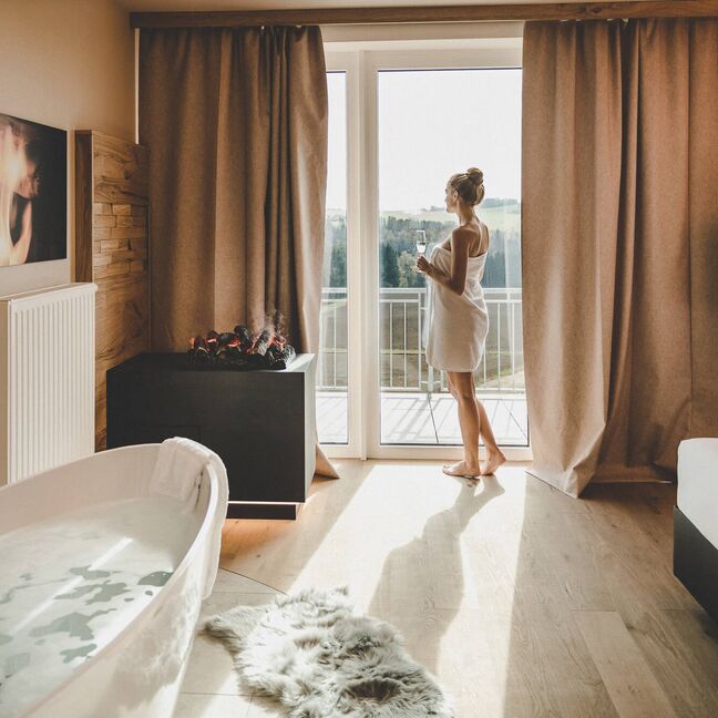 Frau mit Handtuch blickt aus dem Fenster