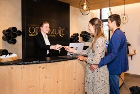 Check In im Wellnesshotel, Paar erhält Informationen an der Rezeption