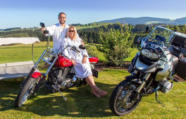 Pärchen im Bademantel auf Motorrad im Wellnessgarten