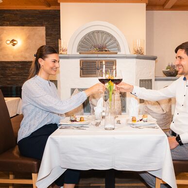 Paar sitzt am gedeckten Tisch beim Abendessen und trinkt Rotwein