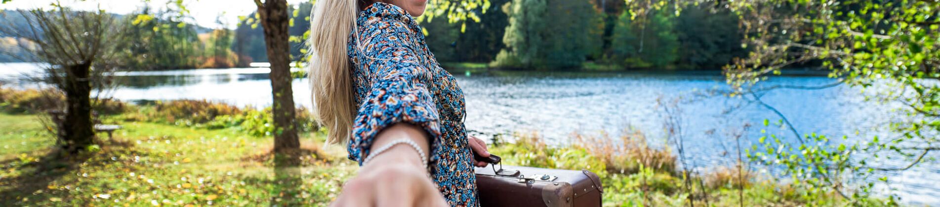 Frau blickt in die Kamera und Streckt die Hand aus