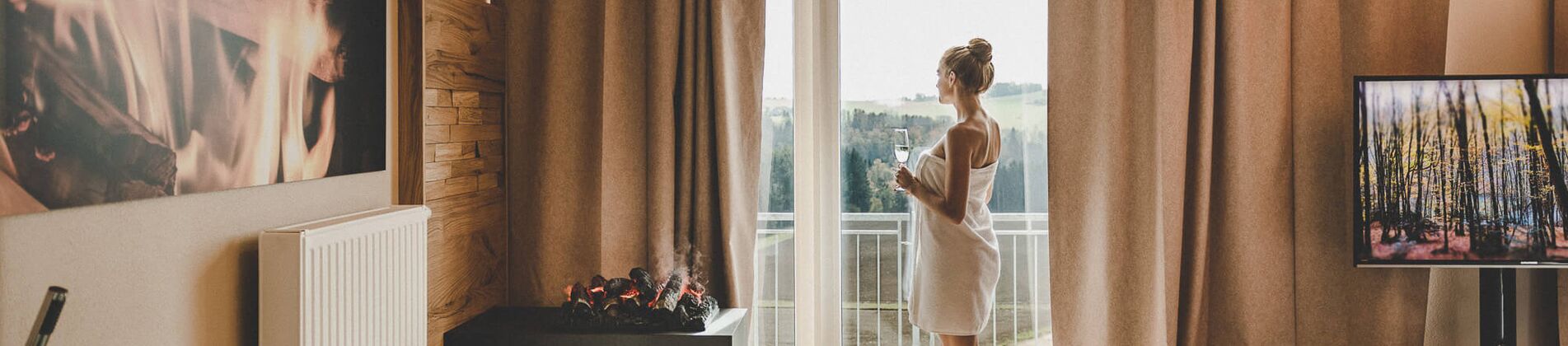 Frau mit Handtuch blickt aus dem Fenster