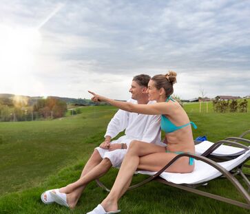 Paar sitzt auf einer Liege und blickt in die Ferne