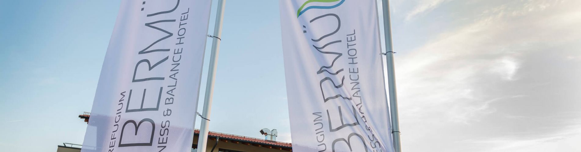 Wehende Fahnen vorm Eingang, im Hintergrund Hotelansicht