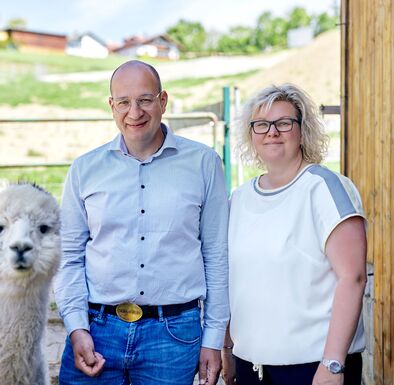 Wolfgang und Michaela Obermüller stehen mit Alpaka vorm Stall