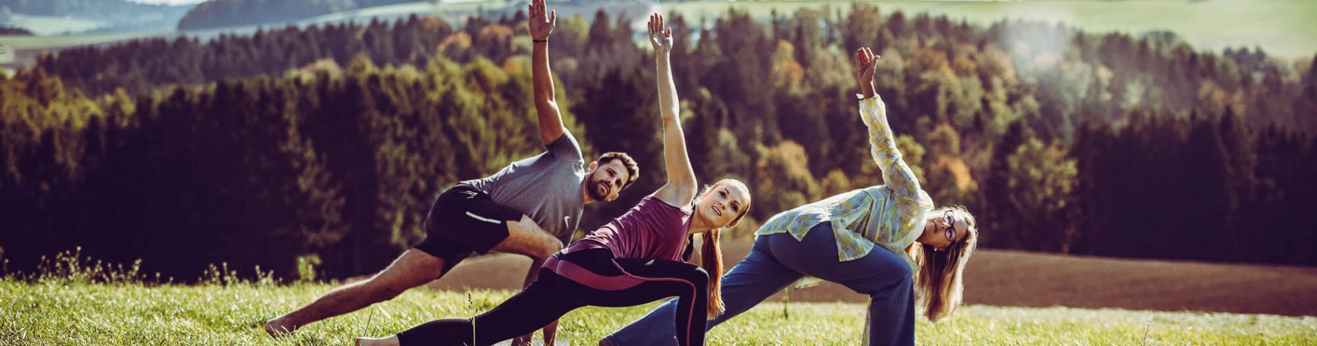 Gruppe macht Qi Gong im Hotelgarten mit herrlichem Ausblick auf Wald und Hügel