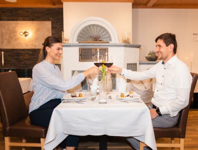 Paar sitzt am gedeckten Tisch beim Abendessen und trinkt Rotwein