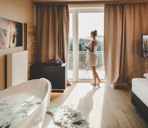 Frau mit Handtuch blickt aus dem Fenster